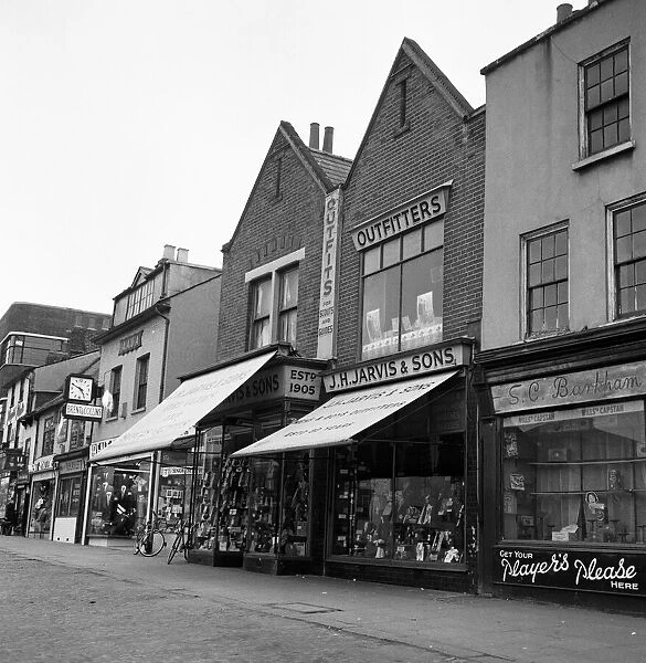 The parade of shops in the market place, Romford, London. 18th March 1960