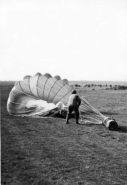 A paratrooper hauling in the parachute attached to a container which has been dropped