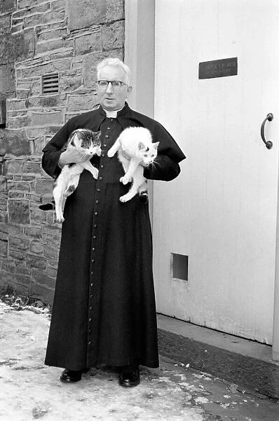 The parish priest seen here gathering up his pet cats February 1970 70-1627-005
