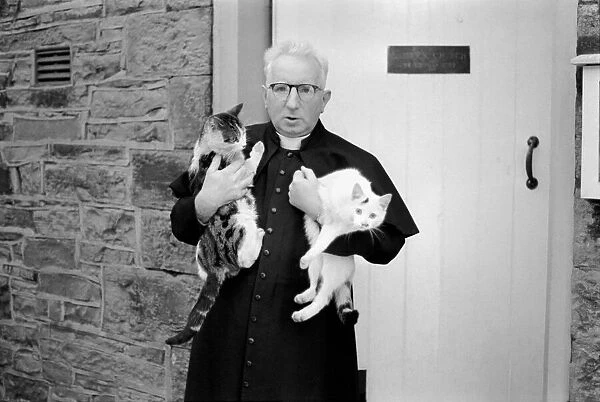 The parish priest seen here gathering up his pet cats February 1970 70-1627-003