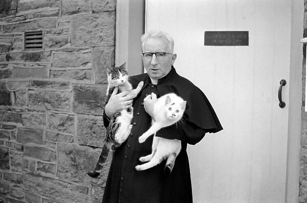 The parish priest seen here gathering up his pet cats February 1970 70-1627-002