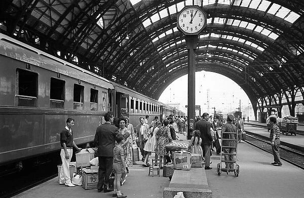 Passengers wait to board the Rome Express at Milan Central Station June 1962