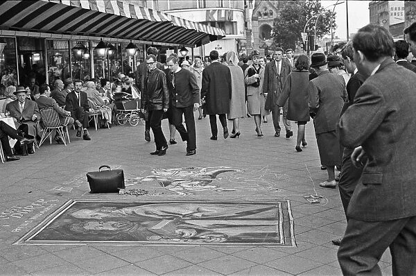 Passers by stop and admire the work of street artists, who uses the pavements of