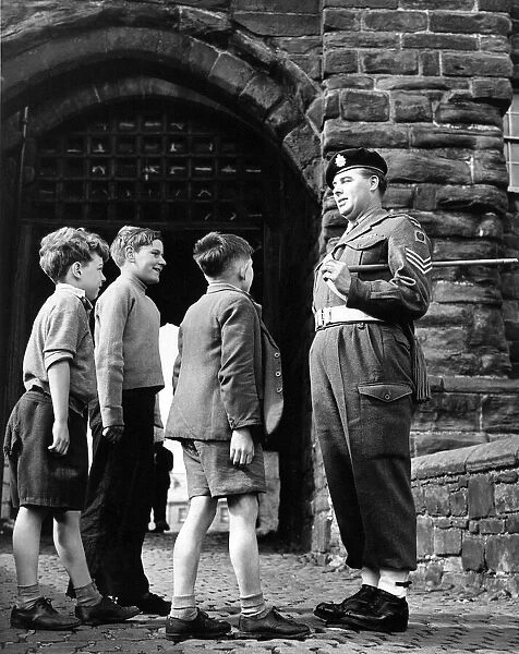 This patient sergeant answers the many questions of these young lads at the gate of