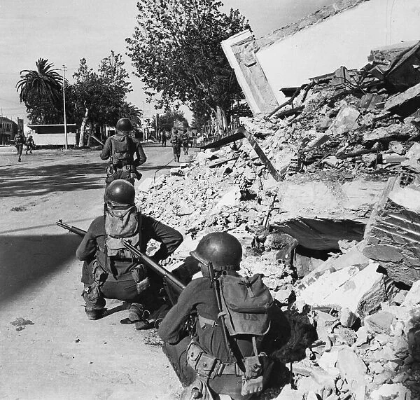 US patrol moves through Bizerta amongst the rubble and devastation of the bombing