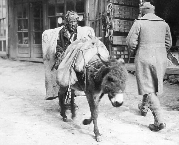 Peasant wearing his winter overcoat brings his goods to market on the back of his donkey