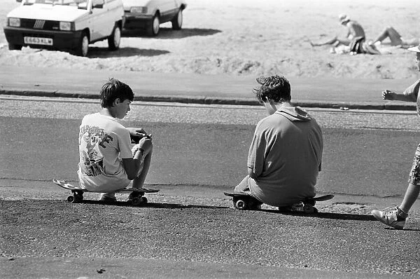 People enjoying a day at Crosby beach. Two boys sitting on skateboards