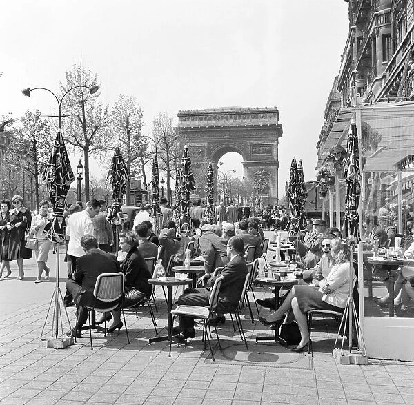 People enjoying the early spring sunshine outside a cafe in Paris near the Arc de