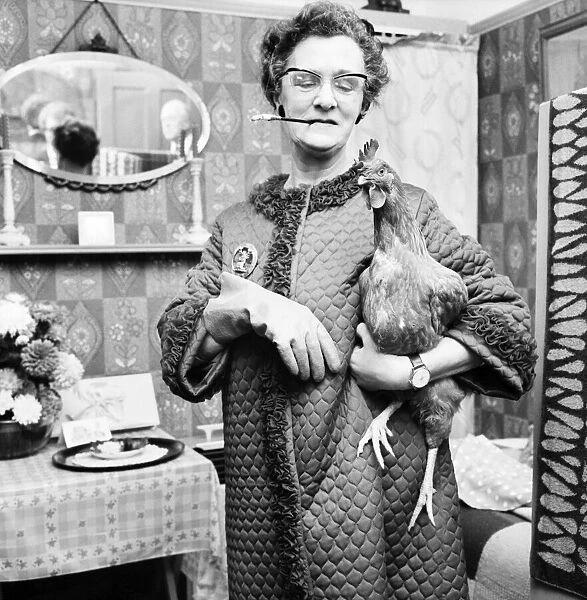 People: Humour: Women: Woman at home holding a chicken in one hand
