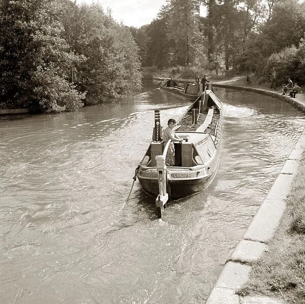 People steering their narrow boats along the canal, with People fishing along