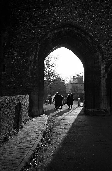 People walk through an arch near St Albans Cathedral, Hertfordshire. Circa 1946