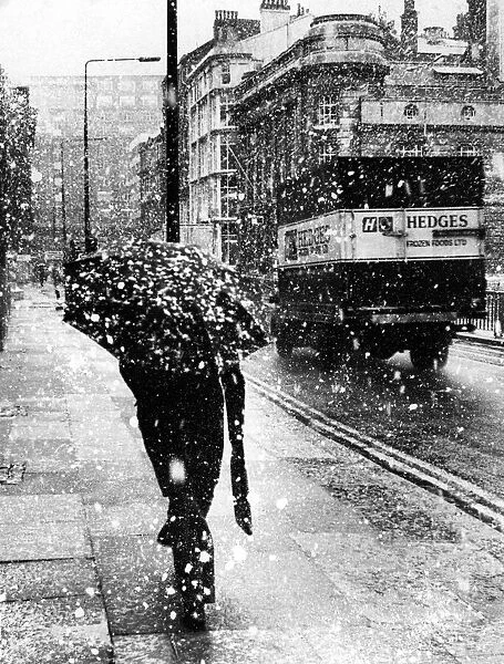 A person walking down the street on a snowy day. 7th January 1971