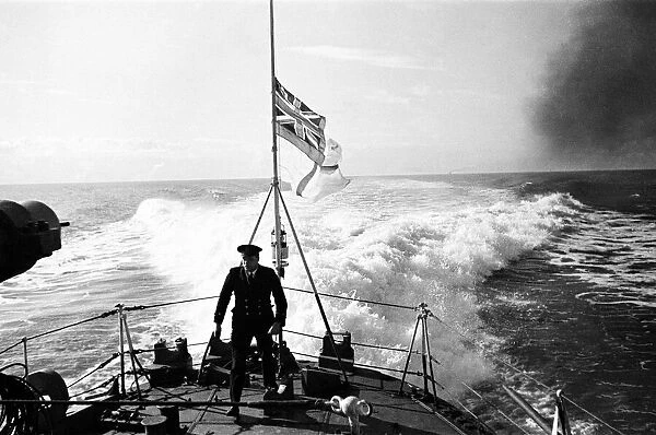 Petty Officer on the quarter deck of a Royal Naval destroyer, White Ensign at half mast