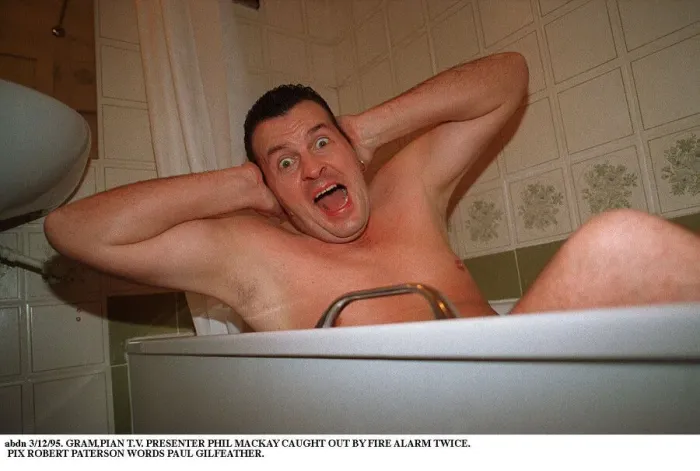 Framed Print : Phil MacKay Grampian TV Presenter in the bath hands on ears Fire Alarm story