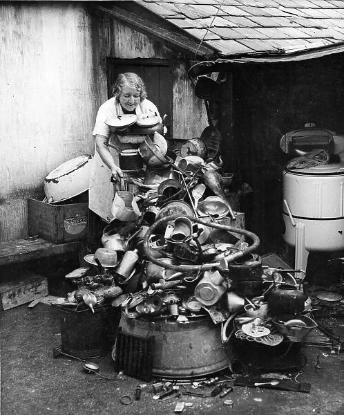 Picture shows a lady salvaging a variety of goods, such as pots and pans, plates, china