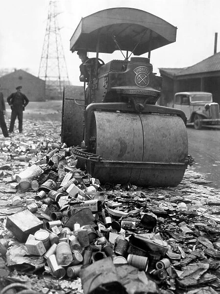 Piles of tin and aliminium cans are crushed by a giant steam roller for salvage as part