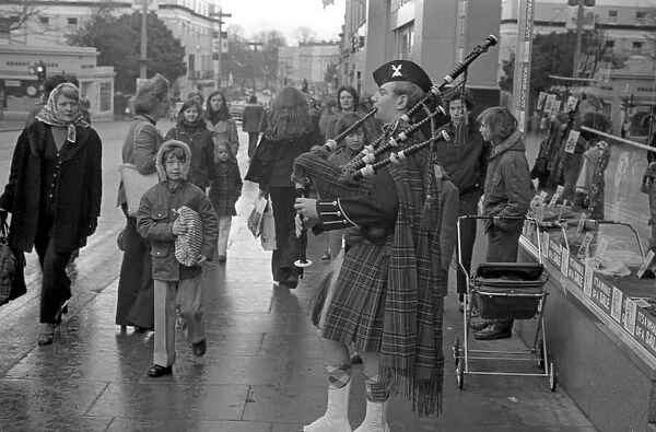 A piper plays the bagpipes dressed in full Scottish national costume including a kilt in