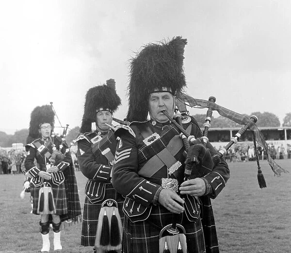 Playing the bagpipes wearing traditional tartan dress at a Highland gathering in Scotland