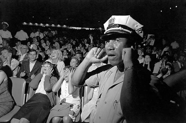 A Policeman puts his fingers in his ears to block out the noise as the Beatles perform
