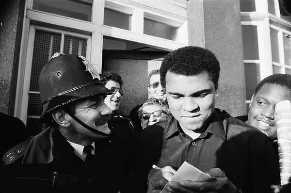 A policeman smiles at Muhammad Ali as he signs autographs in London