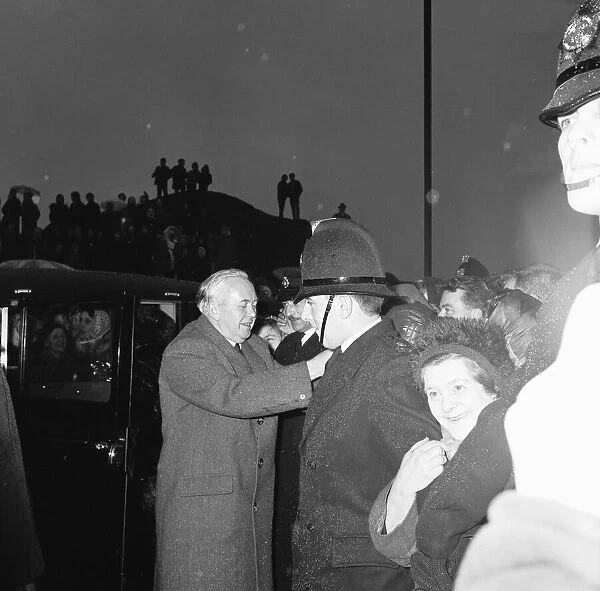 Policemen hold back the crowds as Prime Minister Harold Wilson (1916 - 1995