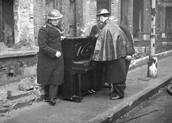 Policemen with a piano help salvage furniture following a V2 attack on Woodbine