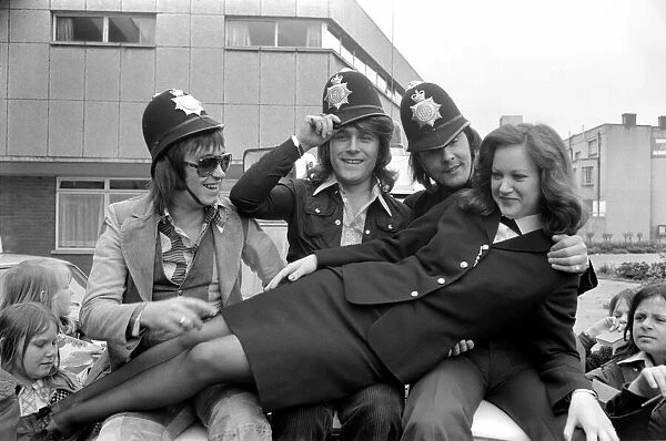 Pop Group 'Mud'. with police officer as they wear pilce helmets May 1975