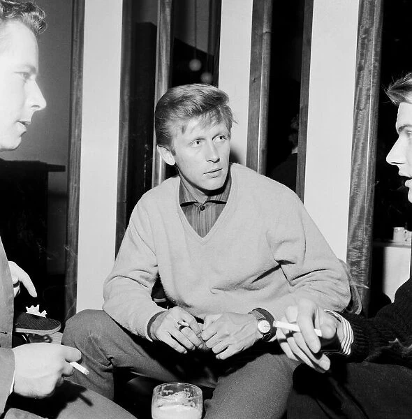 Pop singer Johnny Leyton enjoys a drink and a cigarette with friends