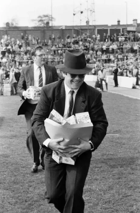 Framed Print : Pop star and Watford FC Chairman, Elton John, handing out Easter eggs to fans Framed Print : Pop star and Watford FC Chairman, Elton John, handing out Easter eggs to fans