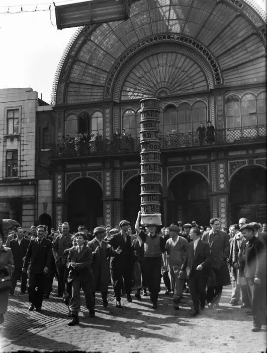 Framed Print : Porters from Covent Garden Flower and Vegetable market race with baskets stacked on their
