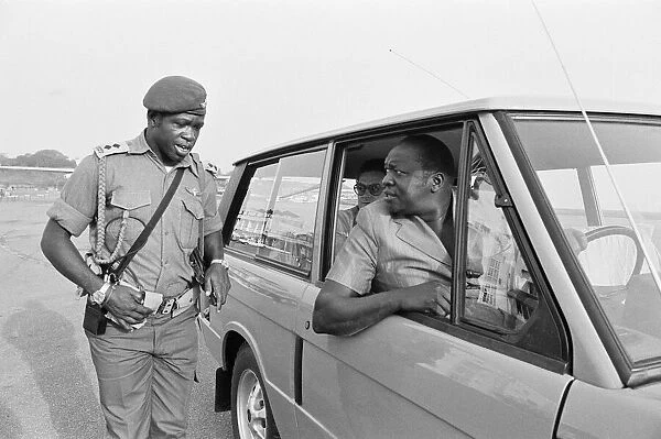 President Idi Amin at the wheel of his Range Rover speaking to one of his bodyguards at