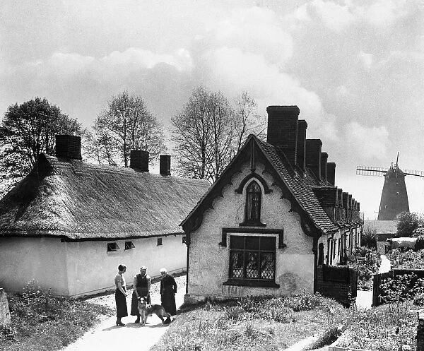 Pretty almshouses and 19th century windmill at Thaxted, North Essex. Circa 1935