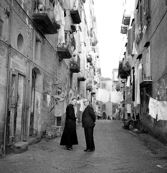 A priest chats to a elderly man in a street in the old town quarter of Naples in Southern