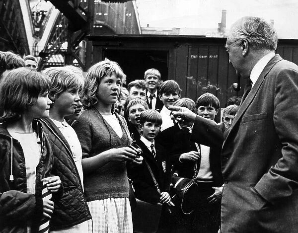 Prime Minister Harold Wilson pauses to chat with a group of children who met his train at
