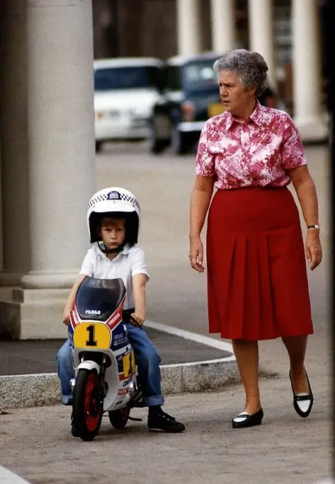 Framed Print : Prince Harry wearing crash helmet and sitting on a toy motorcycle with woman by his side Framed Print : Prince Harry wearing crash helmet and sitting on a toy motorcycle with woman by his side