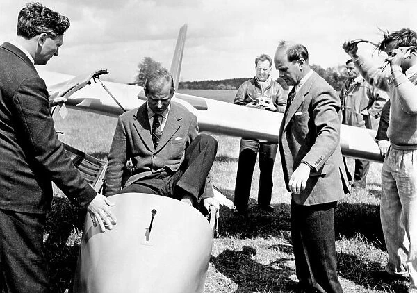 Prince Philip climbs into the cockpit while Peter Scott Looks on (right)