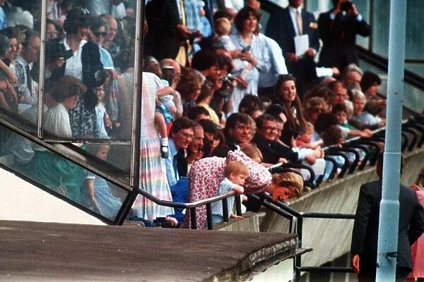 Princess Diana and Prince Harry lean over the railings to shout encouragement to Prince