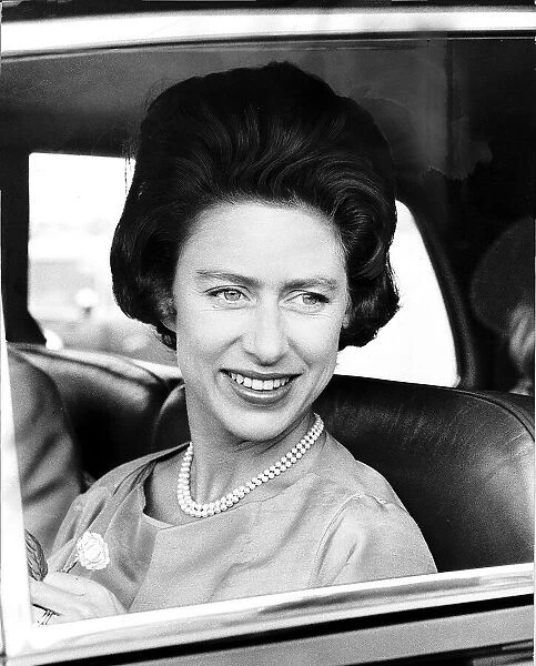 Princess Margaret in 1963 smiles while holding a flower after returning from a holiday in