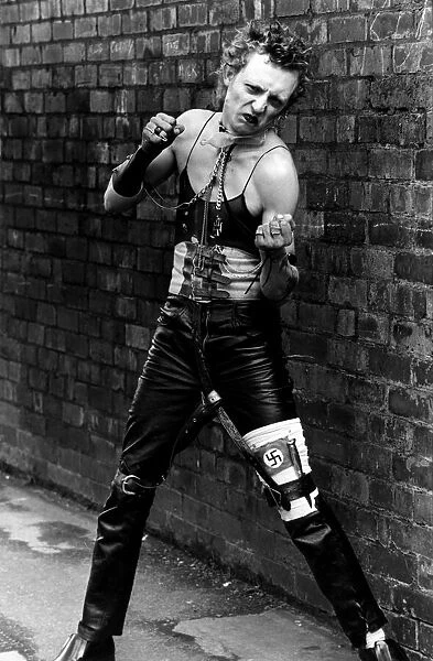 Punk rocker Dancing in the street by a wall wearing a vest top