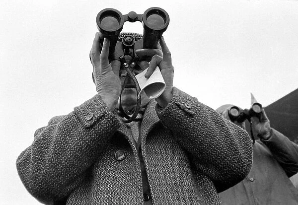 A punter watching the race through binoculars after making his bet march 1963