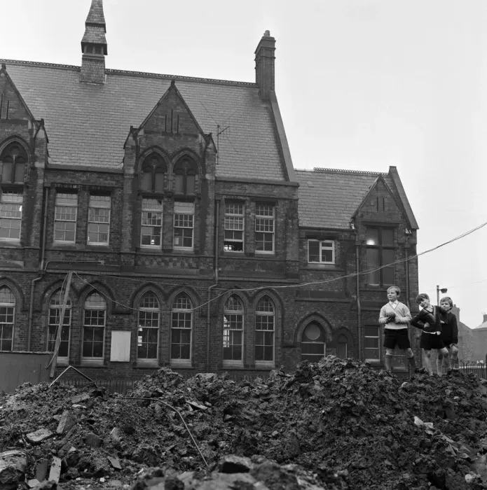 Framed Print : Pupils of Ross Place School, Ardwick, Manchester, jump across a sea of mud to enter Framed Print : Pupils of Ross Place School, Ardwick, Manchester, jump across a sea of mud to enter