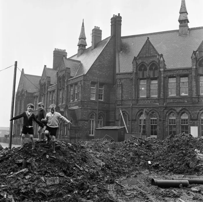 Framed Print : Pupils of Ross Place School, Ardwick, Manchester, jump across a sea of mud to enter Framed Print : Pupils of Ross Place School, Ardwick, Manchester, jump across a sea of mud to enter