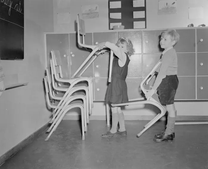 Framed Print : Two pupils seen here stacking chairs following assembly at the new primary school
