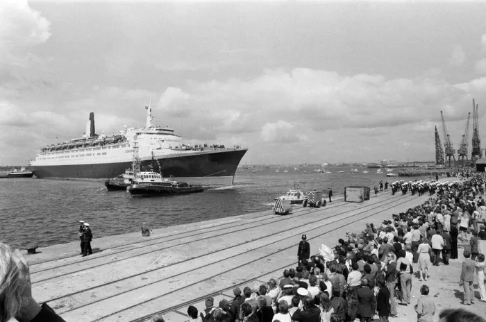 Framed Print : QE2 returns home to Southampton. Union Jacks are festooned on cars, draped on shoulders
