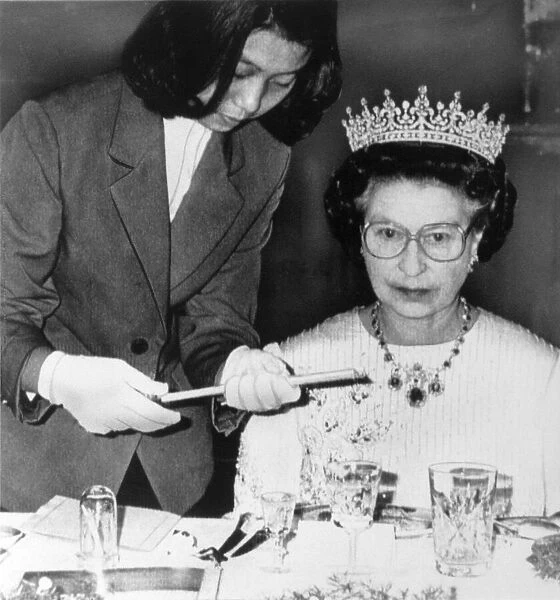 The Queen in China at banquet in Peking. Being handed chopsticks to eat Sea Slugs with
