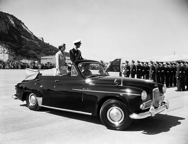 Queen Elizabeth II and the Duke of Edinburgh in an open car reviewing troops on a visit