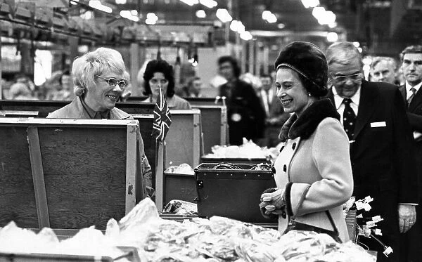 Queen Elizabeth II pauses to talk to one of the women on the assembly line during her