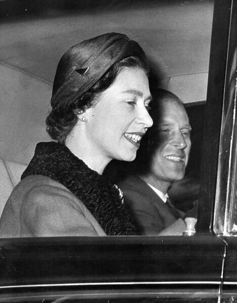 Queen Elizabeth II and Prince Philip smiling as they drive through the streets of