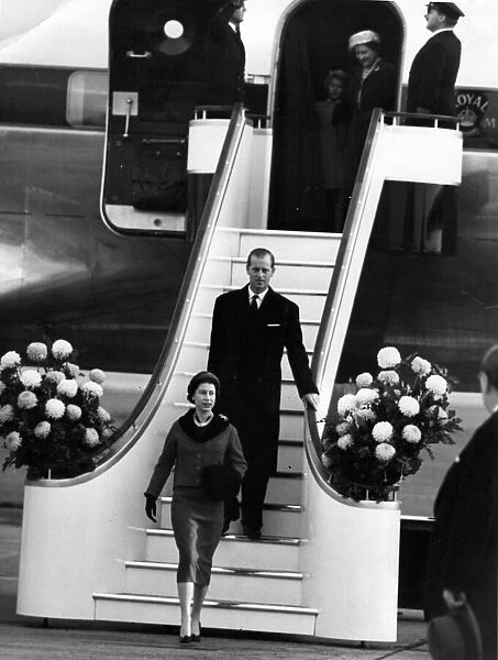 Queen Elizabeth II and Prince Philip walk down the gangway from the plan on their return