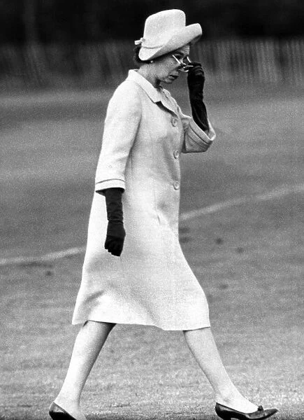 The Queen Elizabeth II walking purposefully across a Polo pitch looking over her